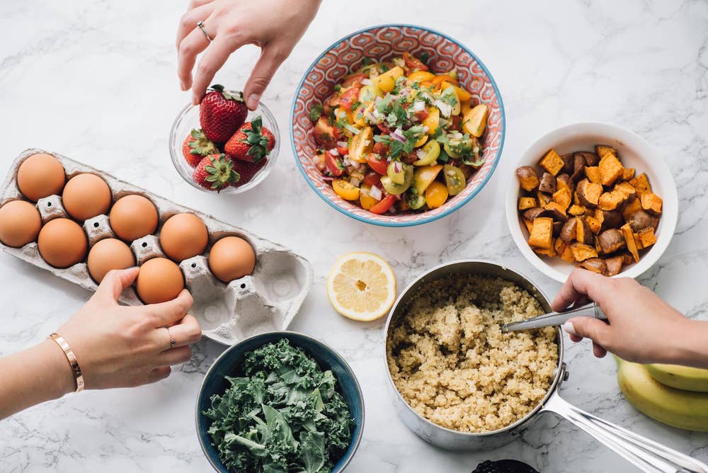 A top down view of a kitchen counter with a finished salad, a pot of rice being stired, and several ingredients