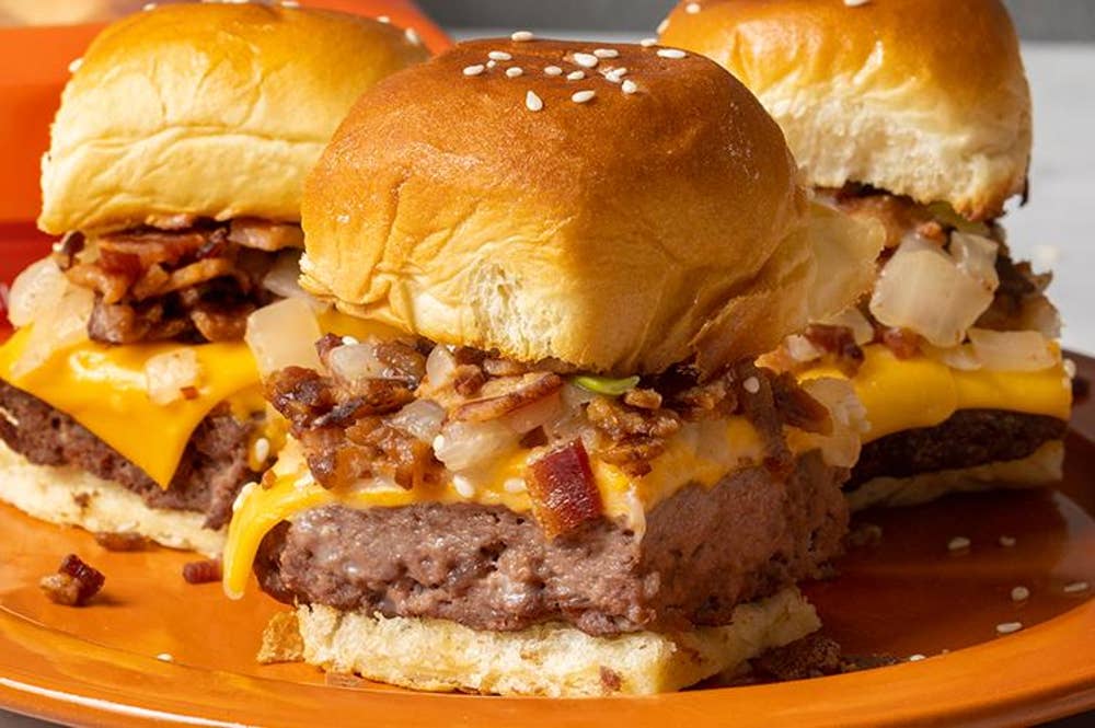 Three cheeseburger sliders sit on a plate