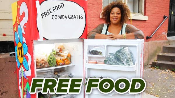 a woman opening a stocked fridge on the street with the words free food on it