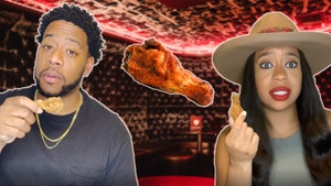 Omari and Nikki holding up a chicken wing.