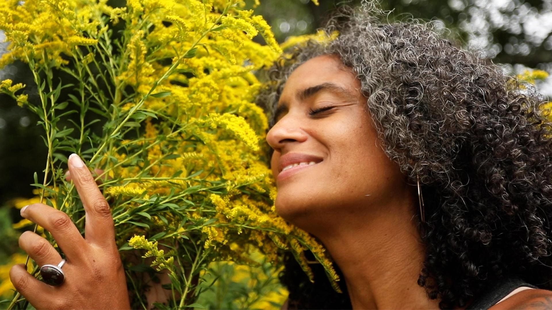 woman smelling goldenrod flowers