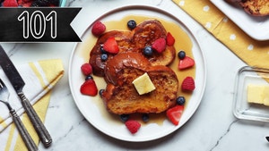 Two french toast slices stacked on a white plate with butter, syrup, and berries on top. Tasty 101 banner in the top left corner