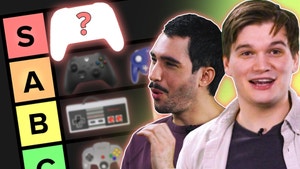 Gaming controllers on the left of screen, one with a red question mark obscuring the image, with two young men on the right of screen, one deep in thought and the other surprised.