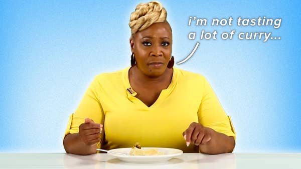 Black woman wearing a yellow shirt and a blonde bun atop her head has a dish of roti in front of her. Text reading "i'm not tasting a lot of curry..." floats to her left.