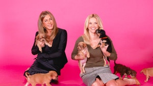 A smiling Jennifer Aniston and Reese Witherspoon hold a bunch of puppies.
