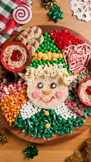 dessert board with numerous candies and desserts themed like Buddy the Elf from the movie Elf, with rice krispy treats as the face and candies for the background