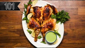 spatchcocked chicken on a serving platter served next to a green sauce